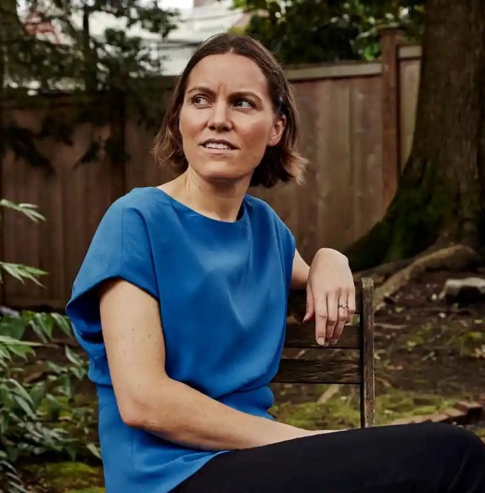 Economist and author Emily Oster seated on chair in yard.