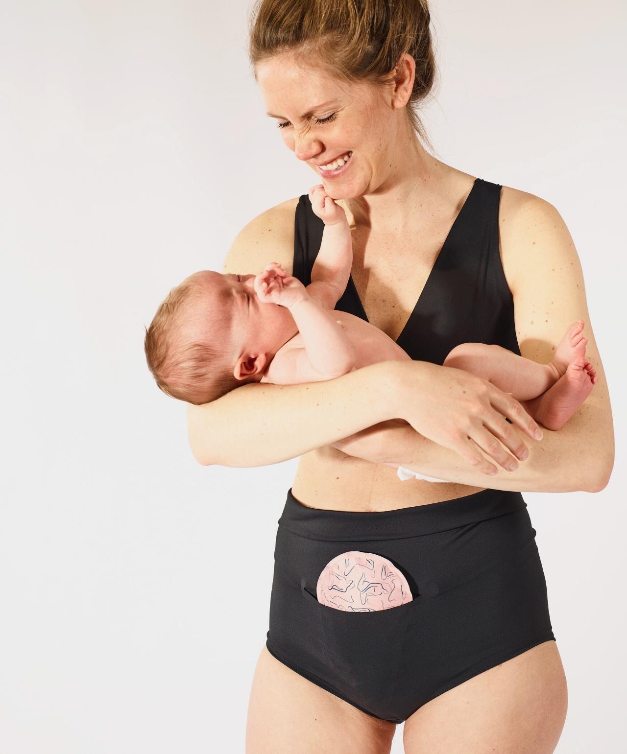 Woman wearing FourthWear Postpartum Bralette & Underwear while holding baby.